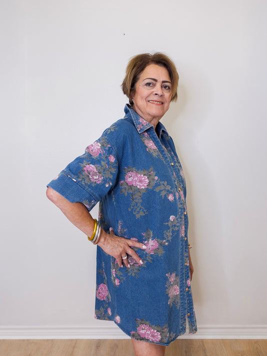 Woman wearing a blue floral dress against a white wall