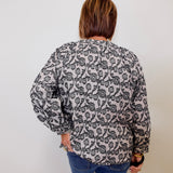 Person wearing a patterned blouse and jeans against a plain background