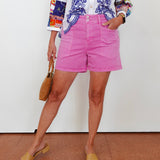 Person wearing a colorful embroidered top and pink shorts against a white background