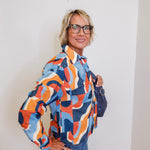 Woman wearing a colorful patterned jacket against a white wall