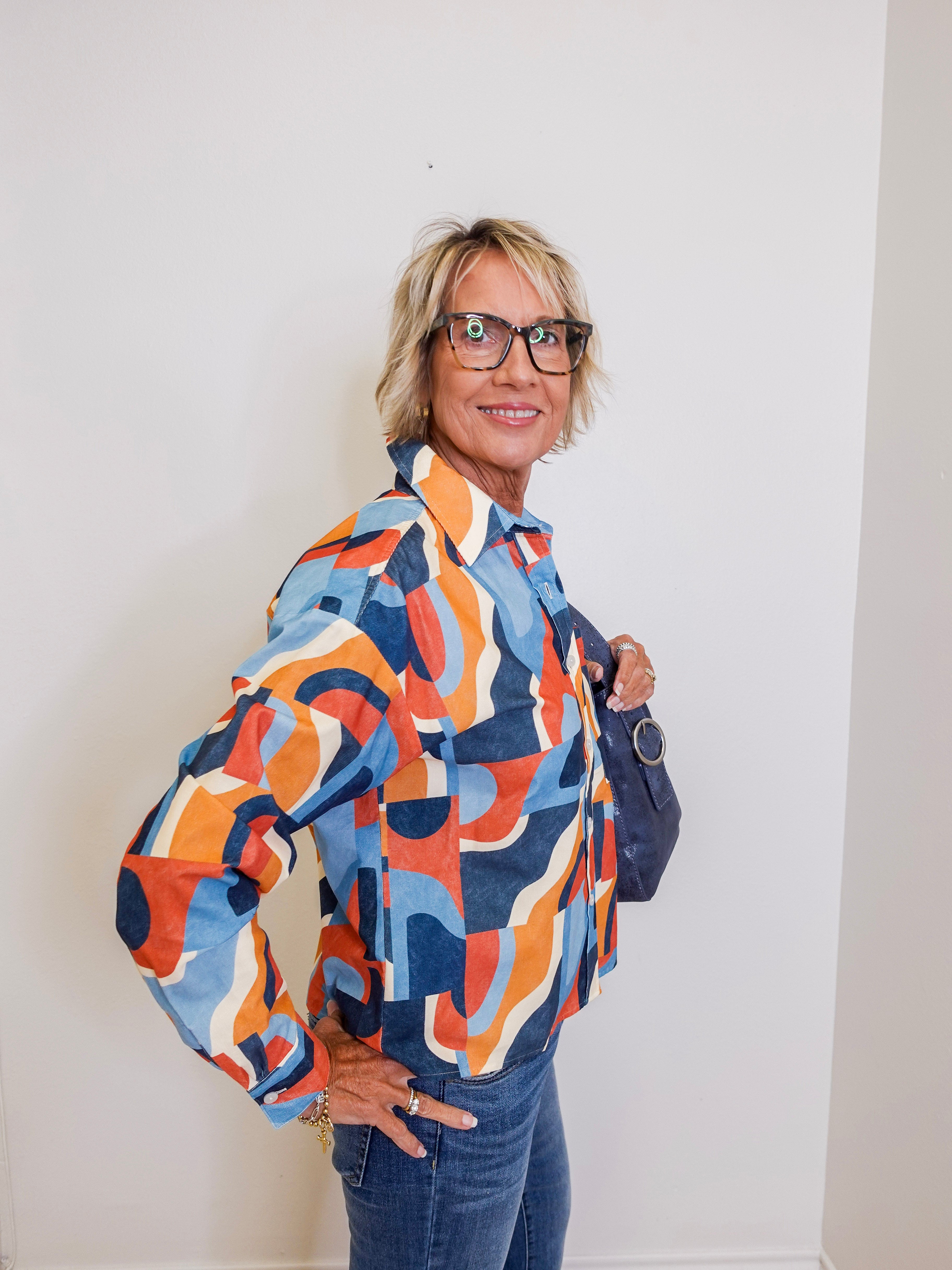 Woman wearing a colorful patterned jacket against a white wall