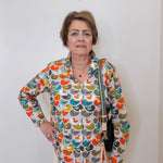 Woman wearing a colorful patterned blouse against a white background