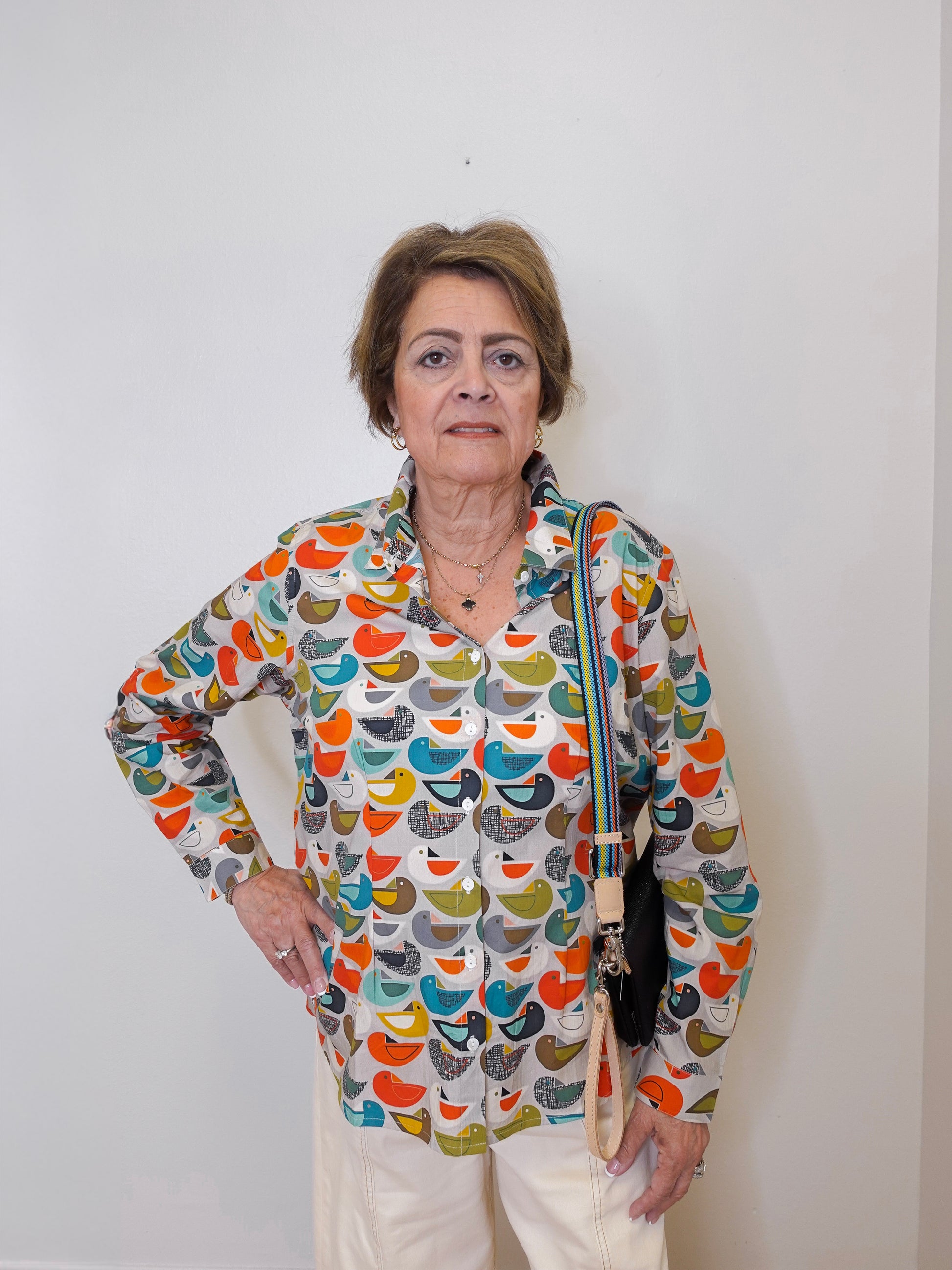 Woman wearing a colorful patterned blouse against a white background