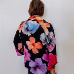 Person wearing a colorful floral kimono against a white background