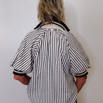 Person wearing a black and white striped shirt against a plain background