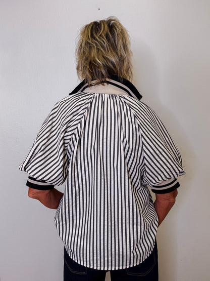 Person wearing a black and white striped shirt against a plain background