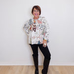 Woman wearing a patterned sweater and black knee-high boots against a white wall.