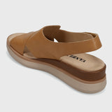 Tan sandal with a visible brand logo on a light gray background