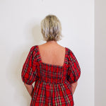 woman wearing a plaid top against a white background. 