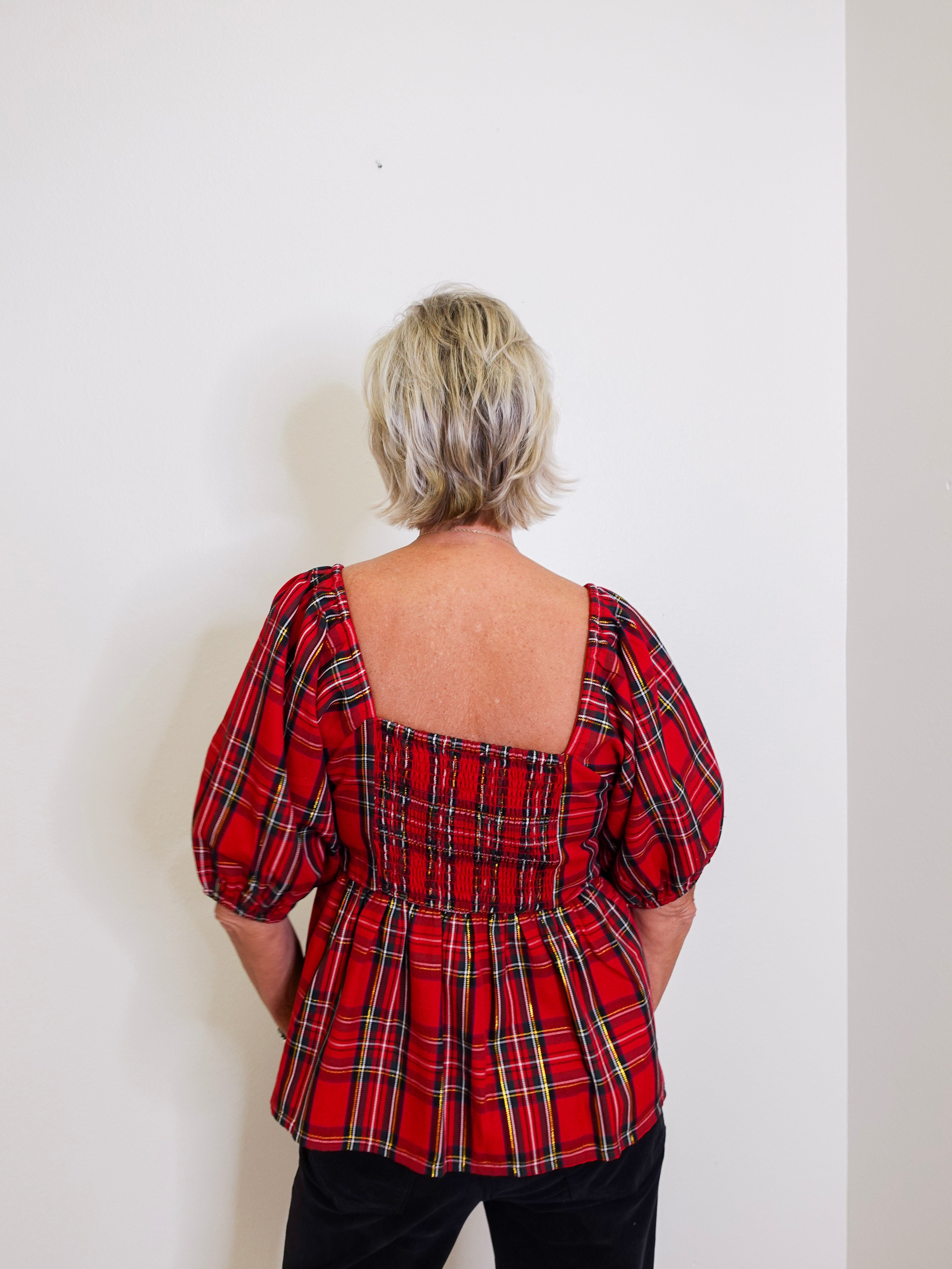 woman wearing a plaid top against a white background. 