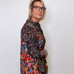 Person wearing a colorful floral and leopard print shirt against a white background