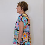 Woman wearing a colorful floral dress against a plain background