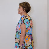 Woman wearing a colorful floral dress against a plain background