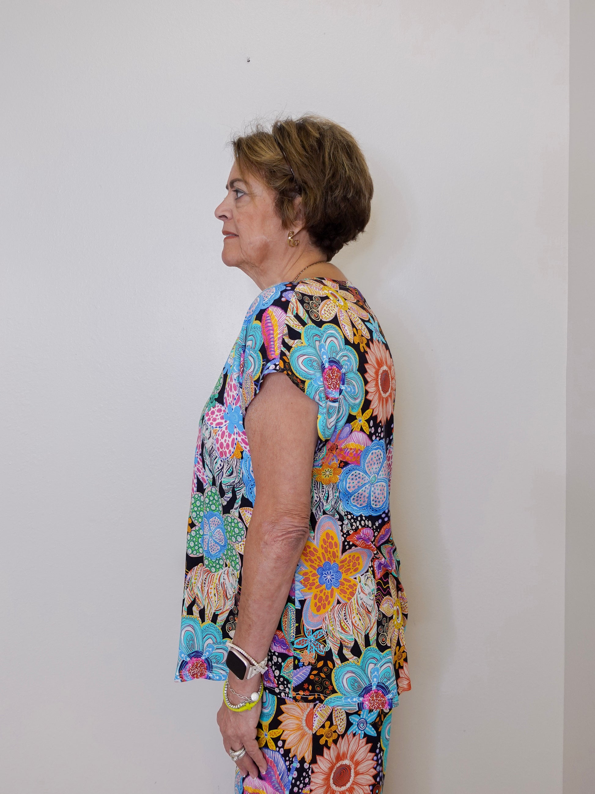 Woman wearing a colorful floral dress against a plain background