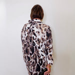 A woman wearing a Joseph ribkoff cowl neck leopard print pullover sweater in front of a white wall. 