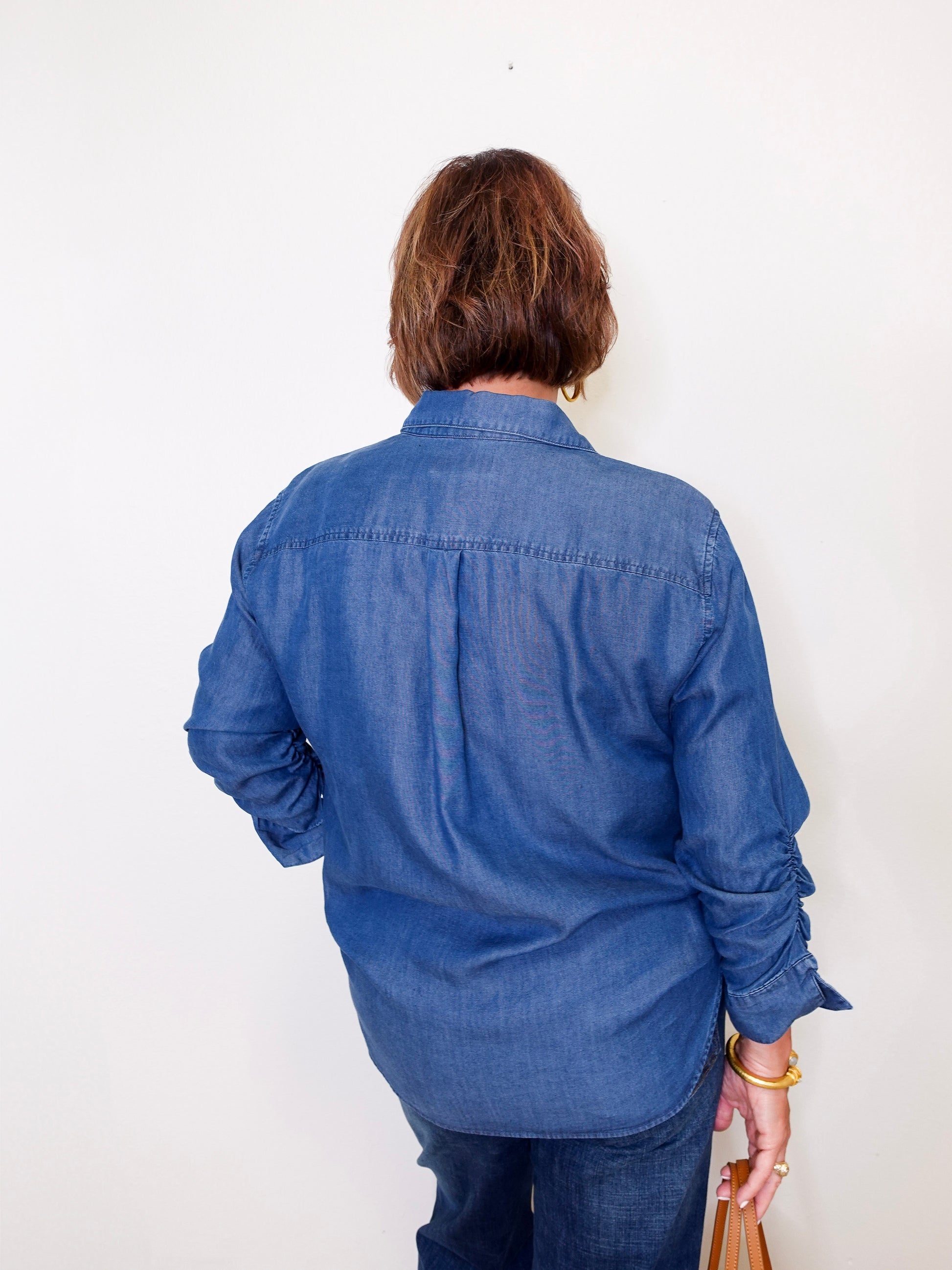 Person wearing a blue Karen Kane denim shirt against a white background