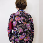 Person wearing a colorful paisley patterned shirt against a white background