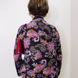 Person wearing a colorful paisley patterned shirt against a white background