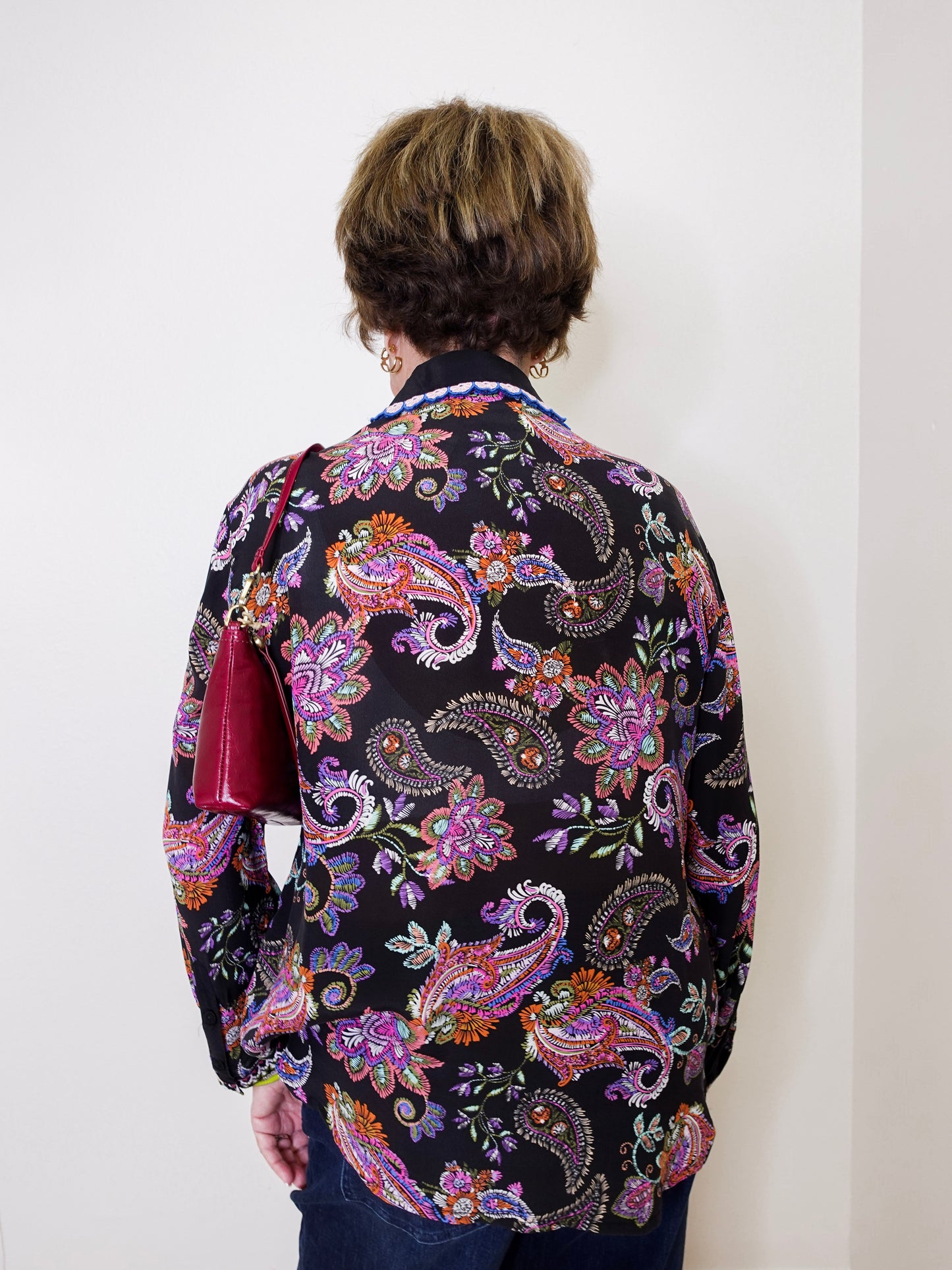 Person wearing a colorful paisley patterned shirt against a white background