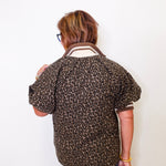 Person wearing a leopard print shirt with rolled-up sleeves on a white background