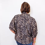 Person wearing a leopard print shirt and blue jeans against a white background