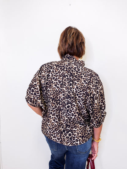 Person wearing a leopard print shirt and blue jeans against a white background