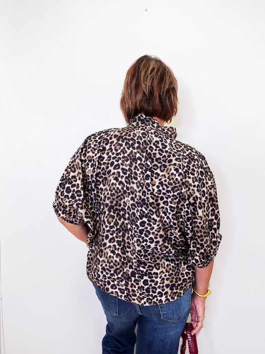 Person wearing a leopard print shirt and blue jeans against a white background