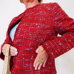 Person wearing a red textured jacket with a plain background