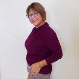 Woman wearing a purple sweater and glasses against a white background