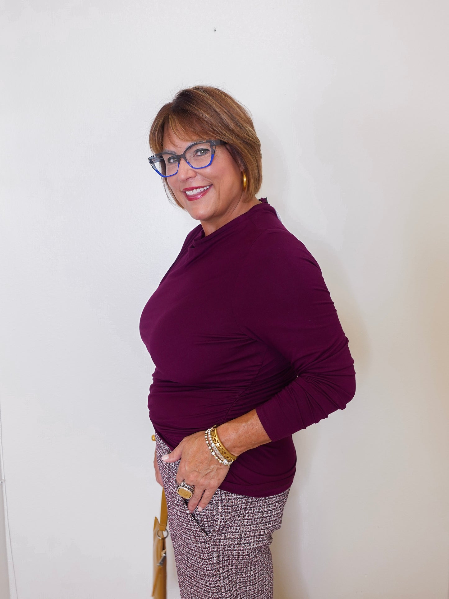 Woman wearing a purple sweater and glasses against a white background