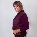 Woman wearing a purple vest over a long-sleeve shirt against a white background