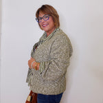 Woman wearing a patterned sweater and glasses against a white wall