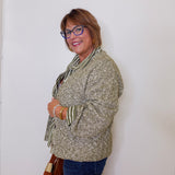 Woman wearing a patterned sweater and glasses against a white wall