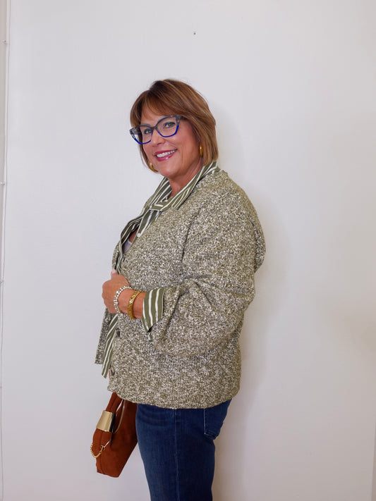 Woman wearing a patterned sweater and glasses against a white wall