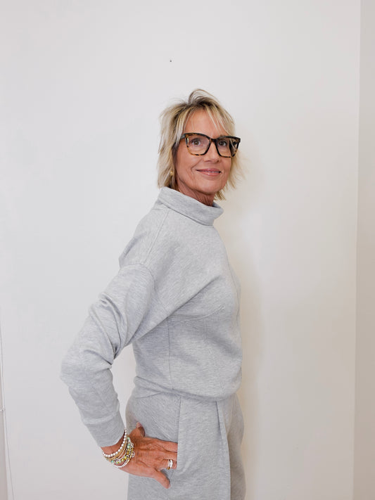 Woman wearing a gray outfit against a white wall
