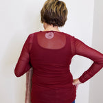 Person wearing a maroon long-sleeve top with mesh back panel against a white background