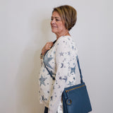 Woman holding a blue handbag against a white wall