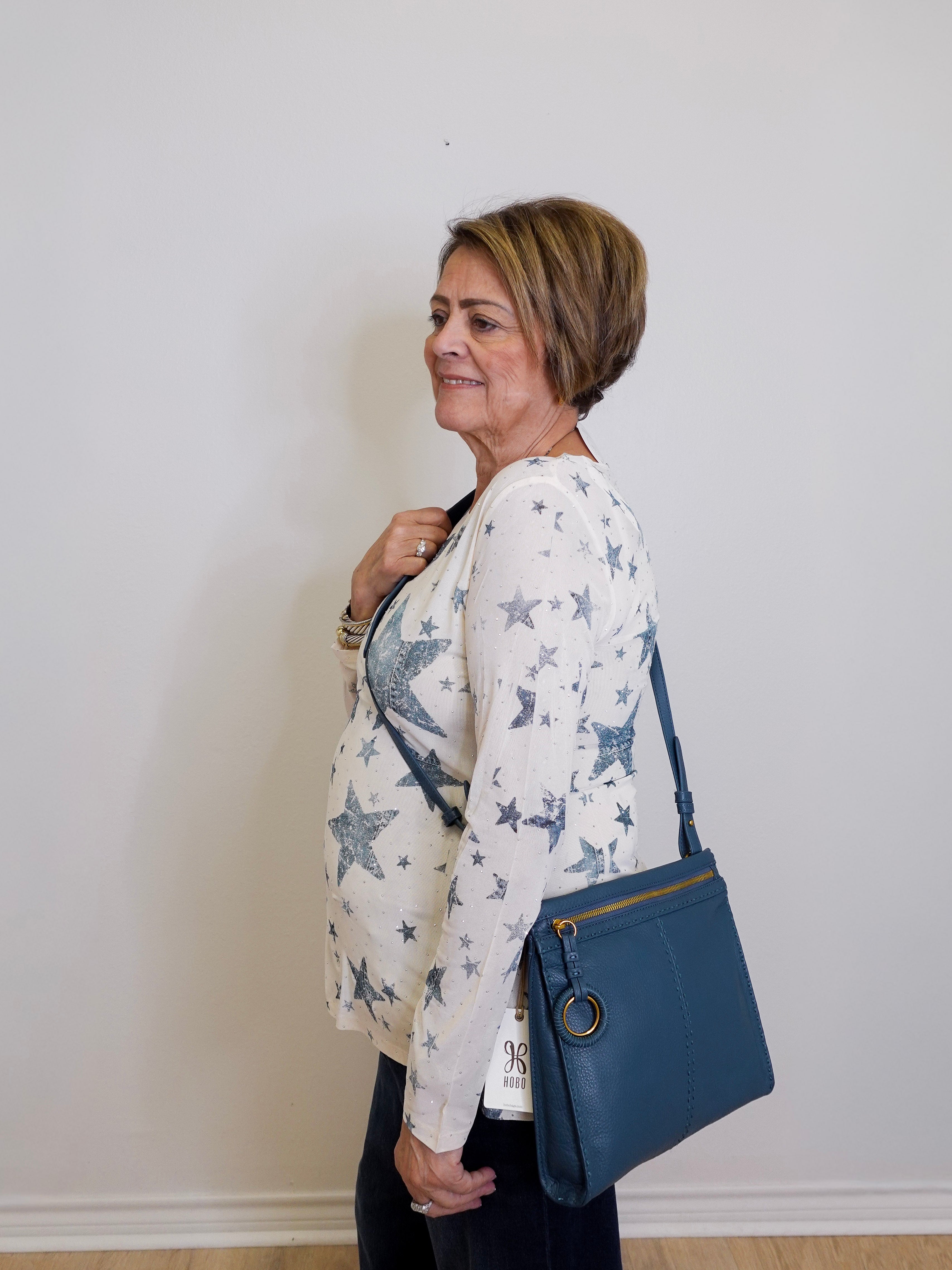 Woman holding a blue handbag against a white wall