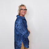 Person wearing a blue floral jacket against a white wall