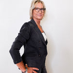 Woman wearing a black blazer and glasses against a white background