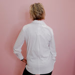 Person wearing a white shirt against a pink wall
