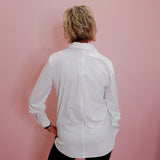 Person wearing a white shirt against a pink wall
