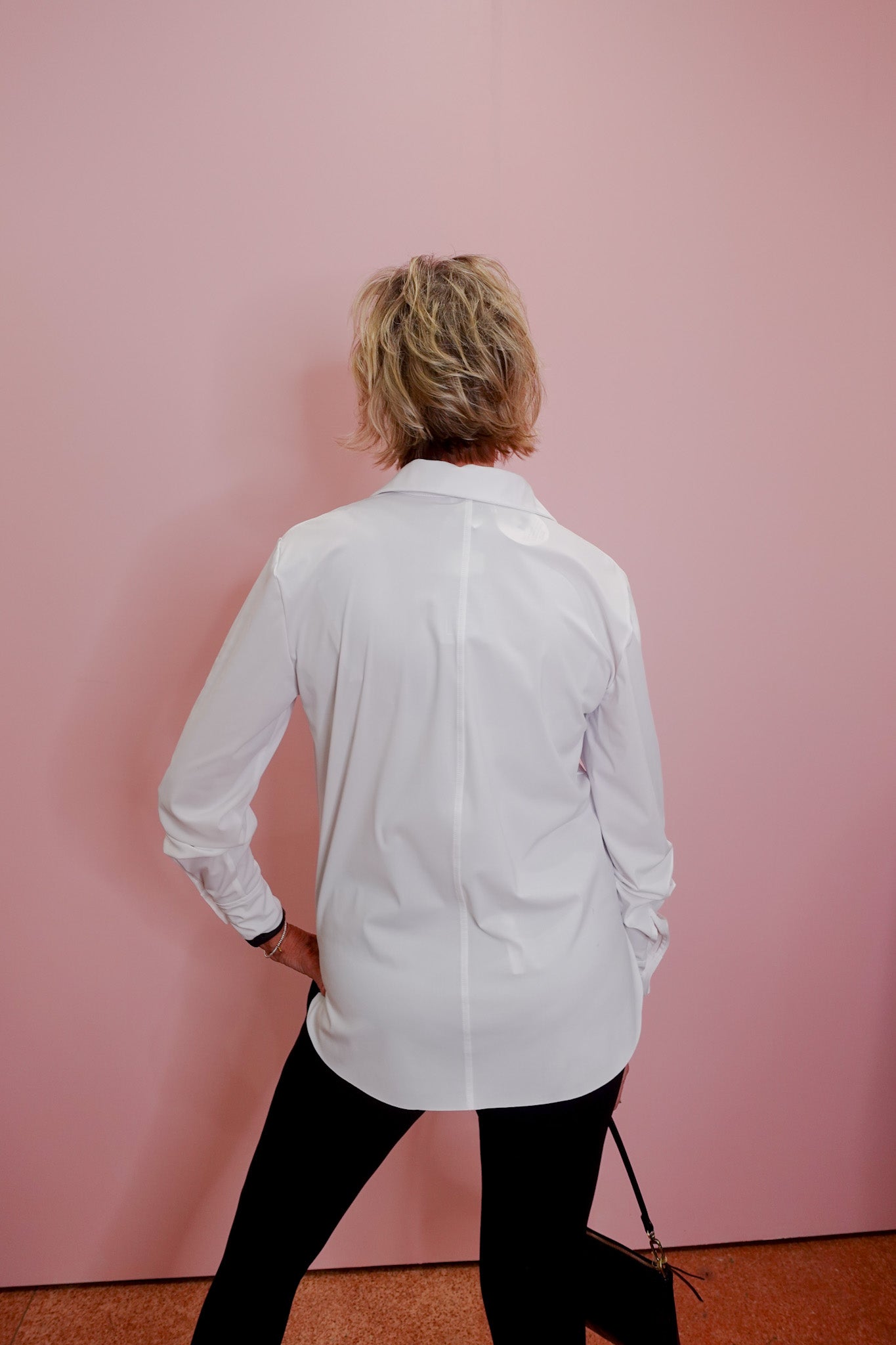 Person wearing a white shirt against a pink wall