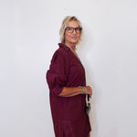 Woman wearing a burgundy dress against a white wall
