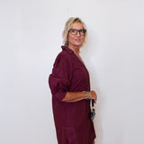 Woman wearing a burgundy dress against a white wall