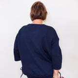 Person wearing a navy blue textured sweater against a white background