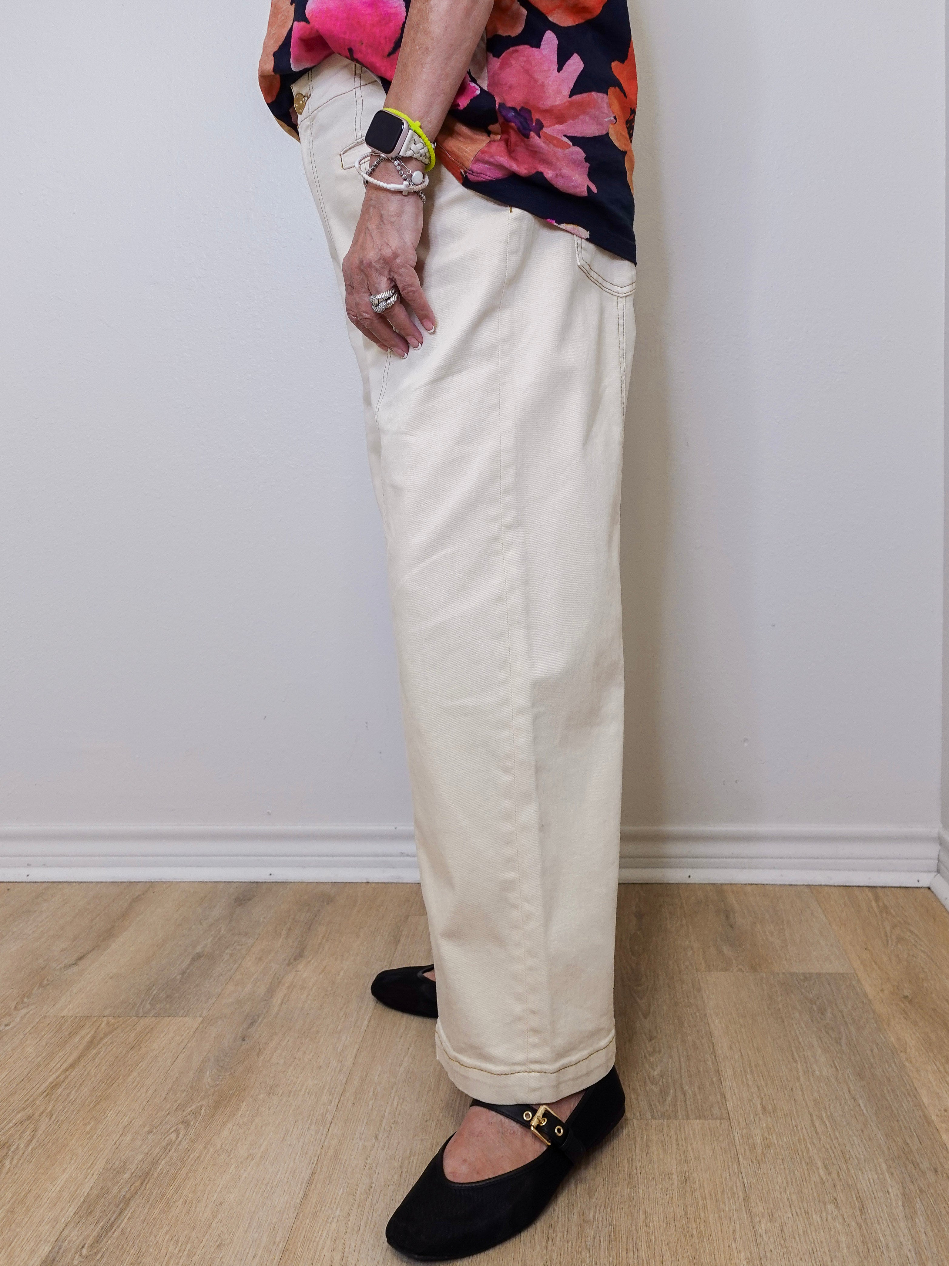 Person wearing a floral top, beige pants, and black shoes on a plain background