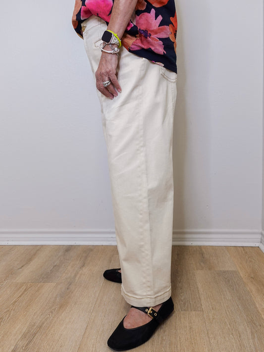Person wearing a floral top, beige pants, and black shoes on a plain background