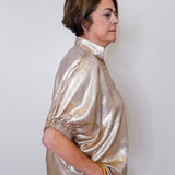 Woman wearing a shiny gold jacket against a white background