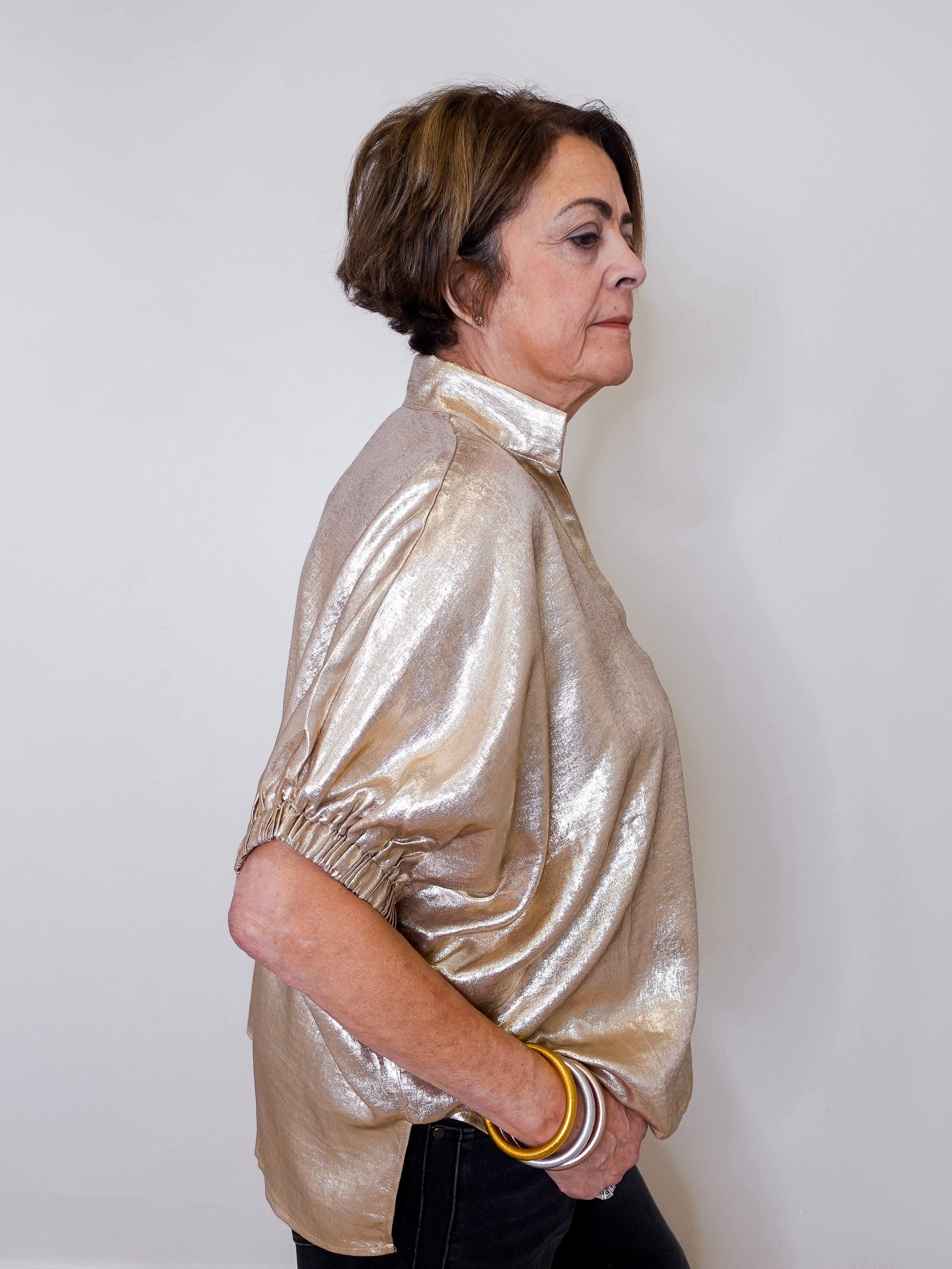 Woman wearing a shiny gold jacket against a white background